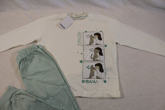 Light green pants and a white long-sleeve top featuring a cartoon girl and dog in comic panels with Japanese text, shown as part of Schlafanzug 110/116 set.