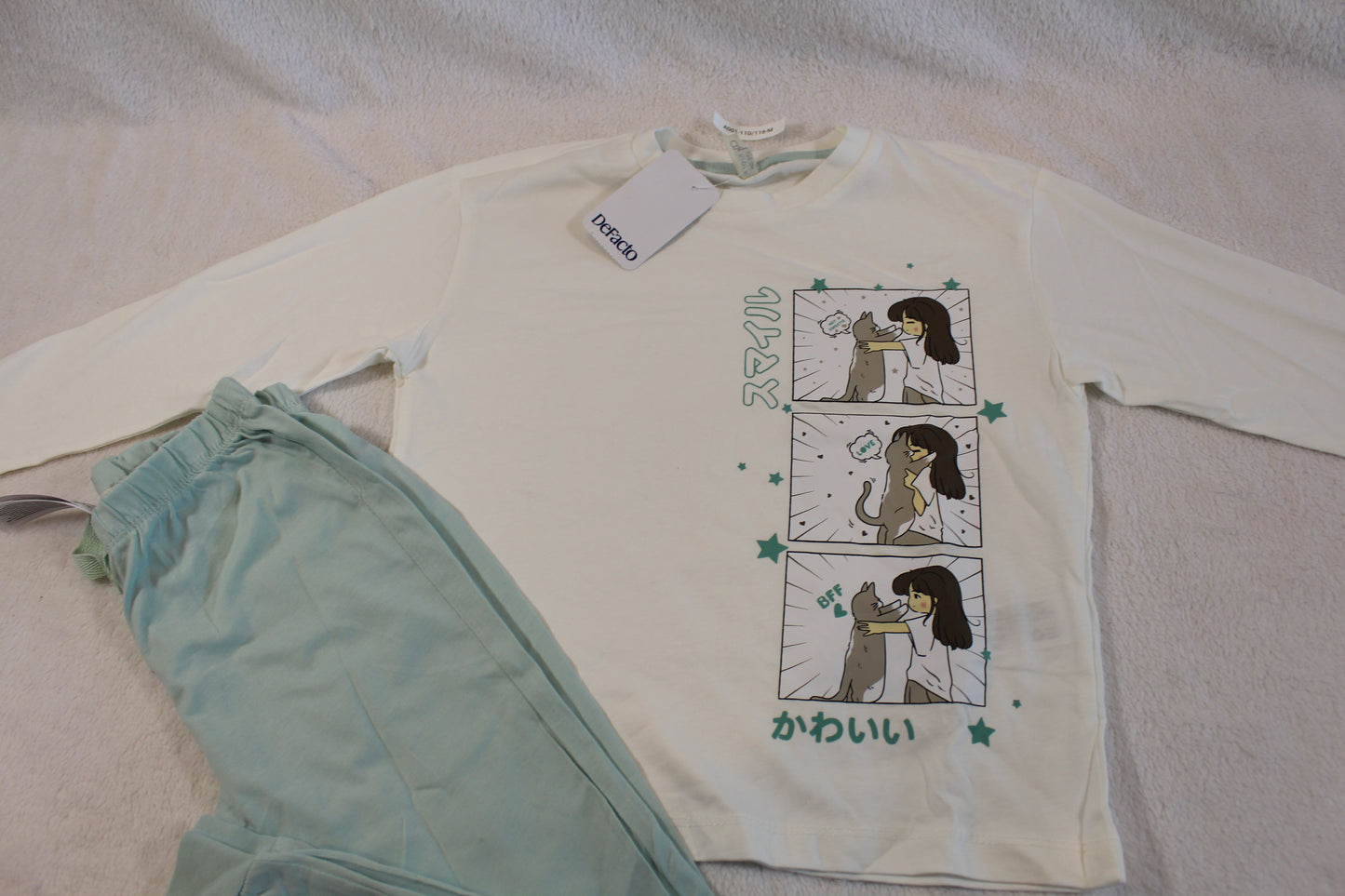 Schlafanzug 110/116 featuring a long-sleeve cream top with a playful cartoon print and matching light green pants, soft fabric suitable for comfortable wear.