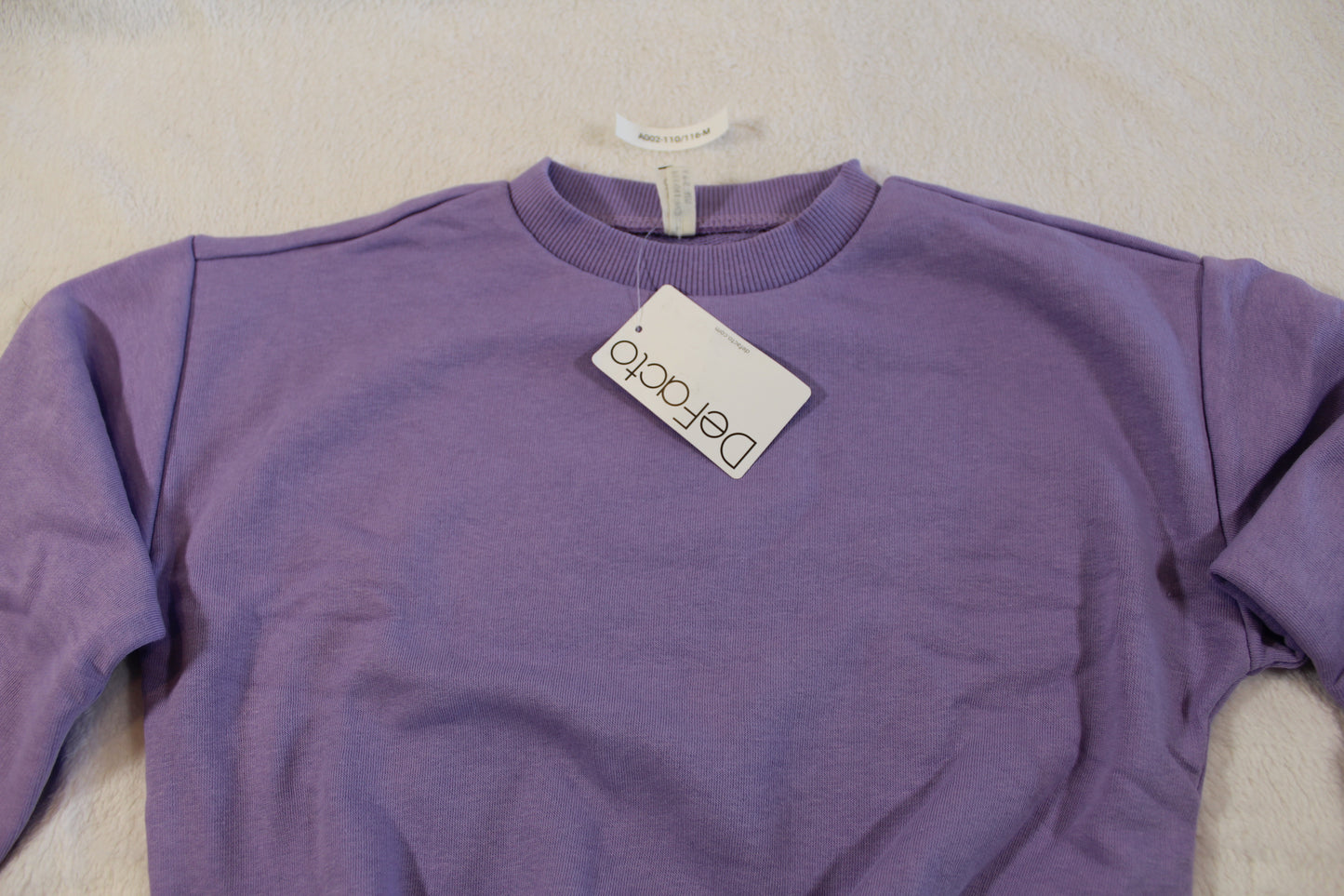 110/116 schöner Uni Pullover in a soft purple color, laid flat showing its simple, comfortable design with a round neckline and long sleeves.
