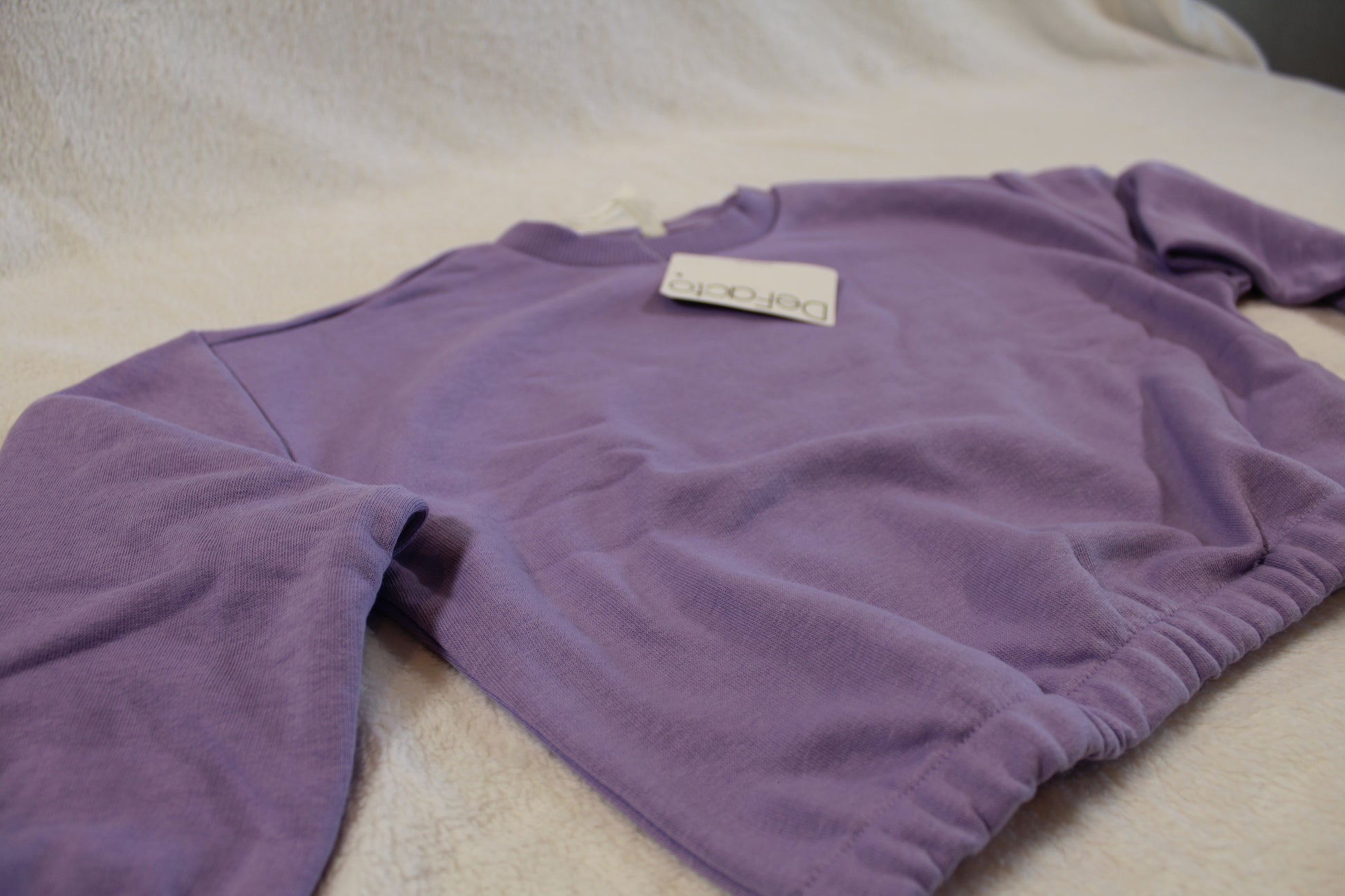 110/116 schöner Uni Pullover in soft purple laid flat on a light fabric background, showcasing long sleeves and a relaxed fit perfect for affordable secondhand Oberteile Hosen und Kleid.