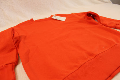 Bright orange long-sleeve soft fabric pullover laid flat with a tag on the collar area, featuring the 116/122 Uni Pullover design.