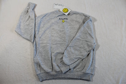 Light grey casual sweatshirt with long sleeves, a small yellow smiley face emblem on the chest, and the label visible on the collar, featuring the 134/140 Monalisa Style Pullover design.